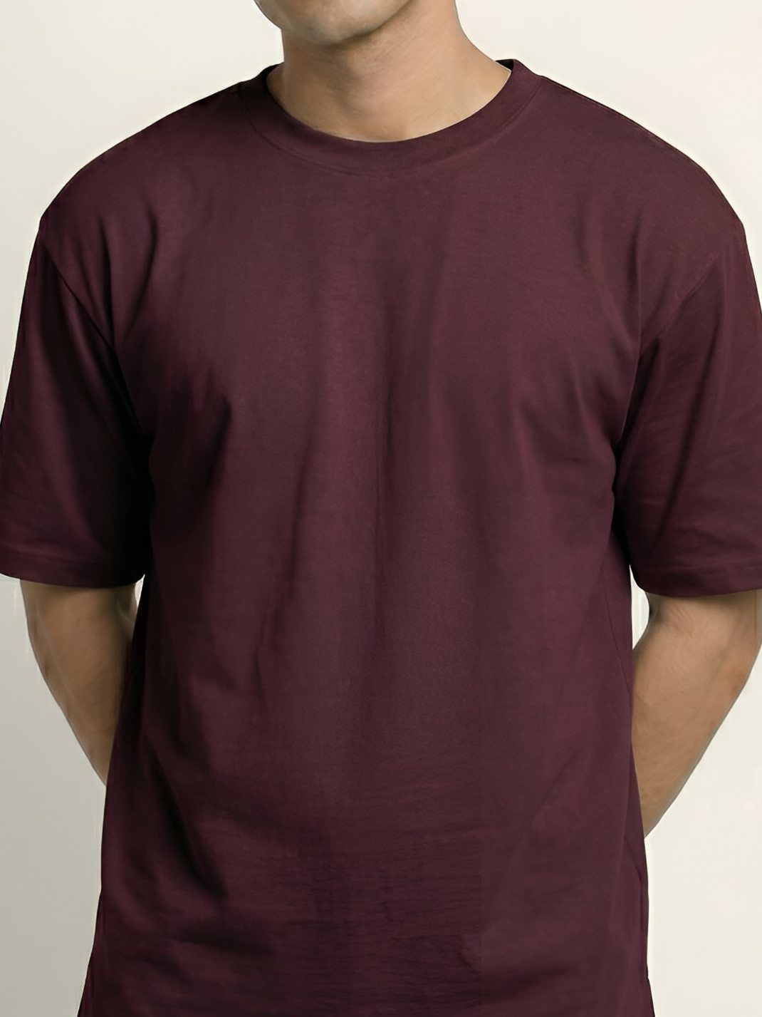 Maroon t-shirt worn by a person on a plain background