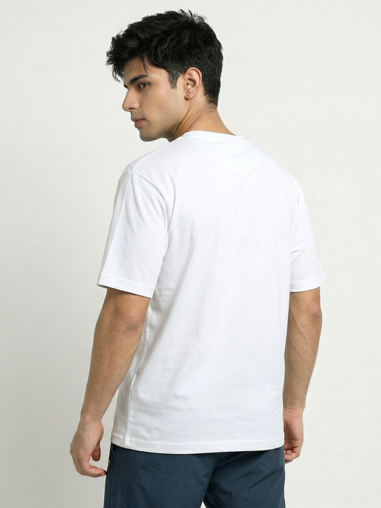 Man wearing a plain white t-shirt against a light background
